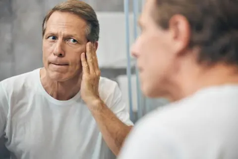 is finasteride safe | white man with grey hair looking in mirror