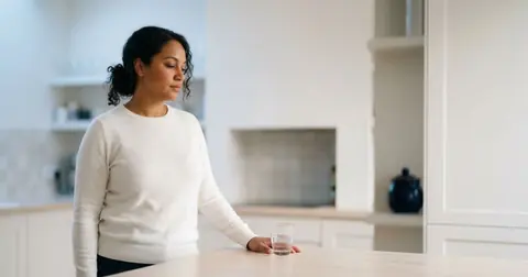 Woman at a kitchen table with a glass of water