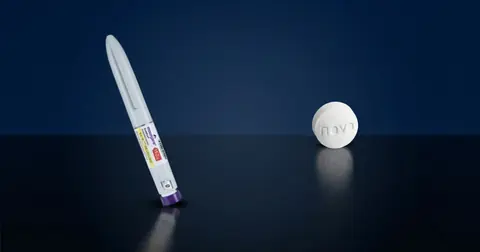 Mounjaro injection pen and Wegovy pill on a dark surface