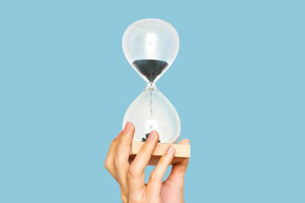 A person holds an hourglass, symbolising the passage of time