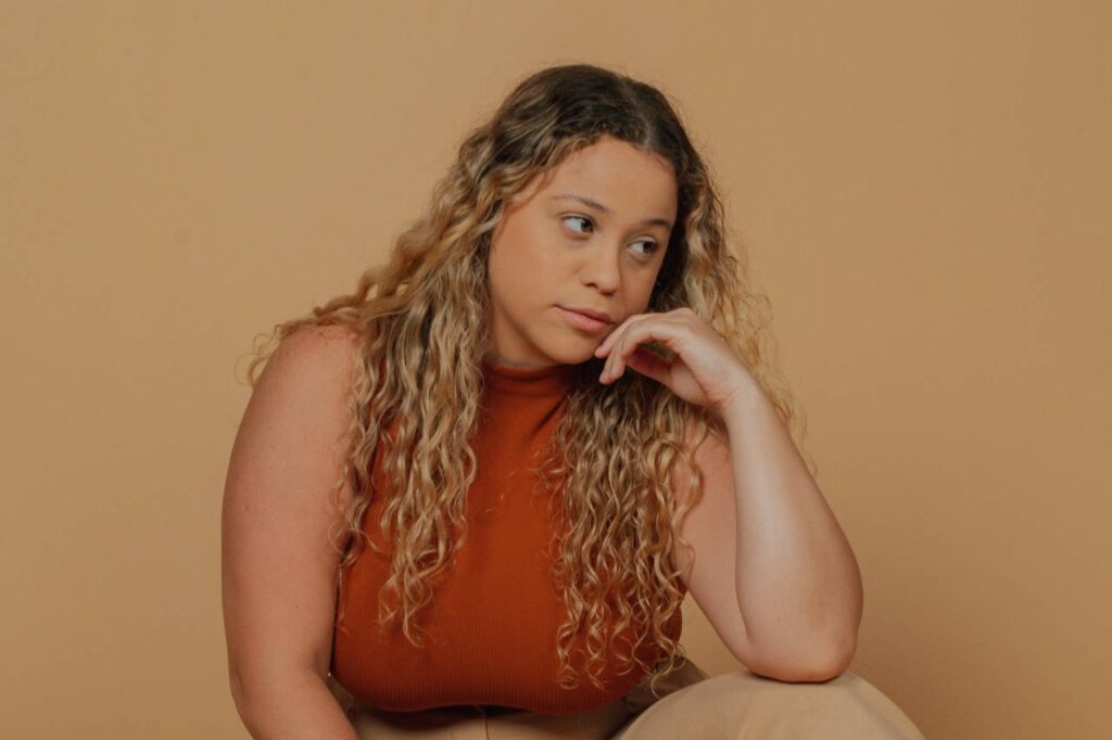 side effects when switching from mounjaro to wegovy | woman in orange top sat down resting elbow on knee
