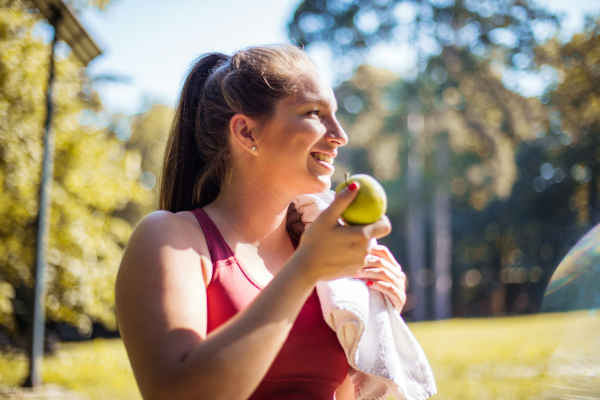 how does wegovy work | woman in exercise clothes eating an apple in a park