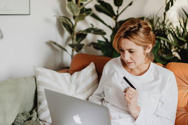 safely buy glp-1 medication for weight loss online | red-haired woman on orange sofa with credit card and laptop