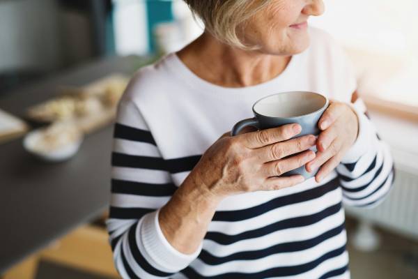 mounjaro and hrt | woman wearing striped jumper drinking tea in kitchen