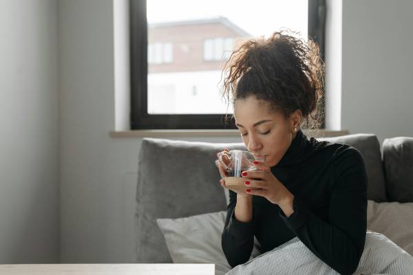 How to Stop Feeling Sick on Wegovy | woman in black long sleeve t-shirt on the sofa drinking tea
