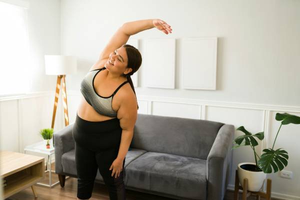 mindset tips for weight loss this new year | woman doing yoga in front of sofa in living area