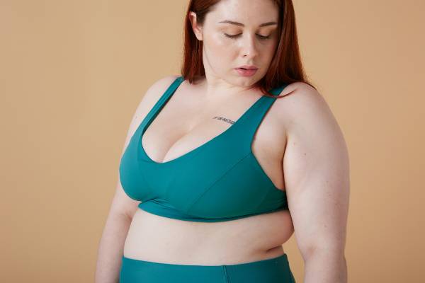wegovy injection sites | woman in green sports bra against neutral background looking down
